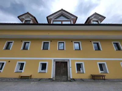 a yellow building with a door and two benches at Stara Pošta Apartment 8 in Grosuplje