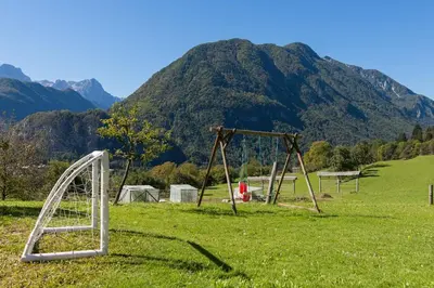 an empty swing set in a field with a mountain at Ela Apartments - 1 in Kranjska Gora