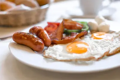 a plate of breakfast food with eggs sausage and bacon at B&B Bau in Maribor