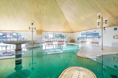 a swimming pool with a green tile floor in a building at Terme Banovci - Hotelsko naselje Zeleni gaj in Banovci