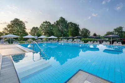 a large blue swimming pool with chairs and umbrellas at Terme Banovci - Mobilne hiške Med Brajdami in Banovci
